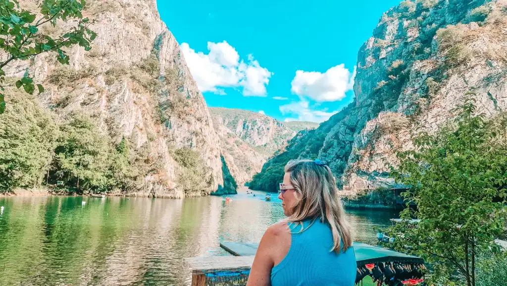 Em gazing out over the emerald waters of Matka Canyon in North Macedonia, surrounded by steep rocky cliffs and peaceful nature, perfect for kayaking and hiking.