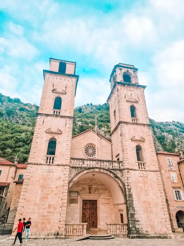 The twin towers of Kotor Cathedral in Montenegro rise against the green hillside, a highlight of exploring the historic Old Town's mediaeval wonders.