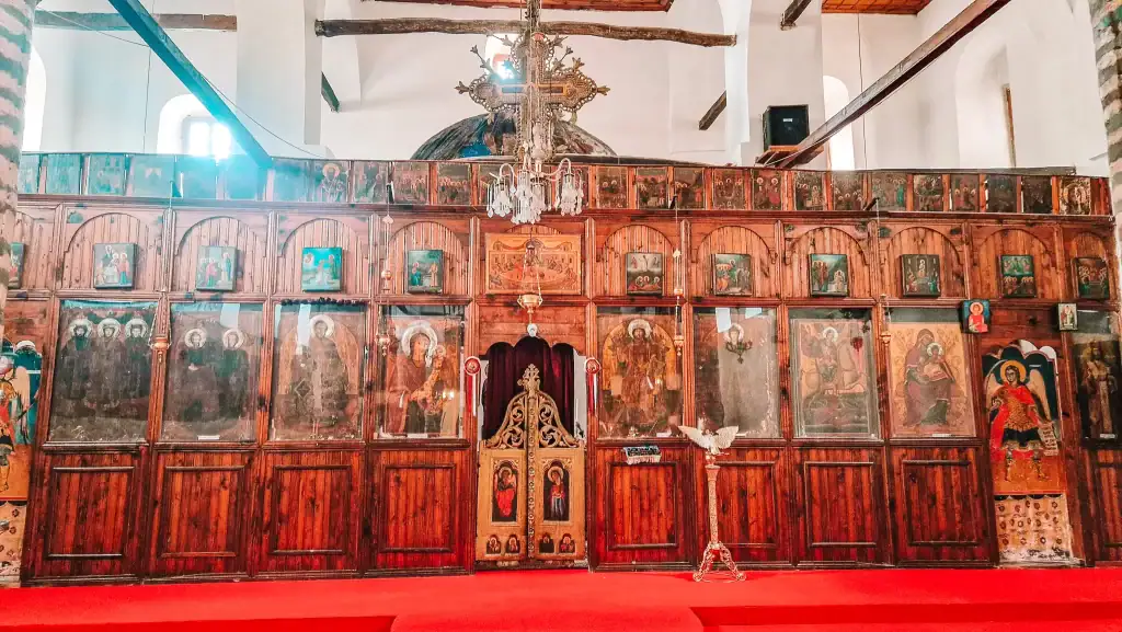 Ornate wooden iconostasis covered with religious paintings and gold details inside an Orthodox church in Berat.