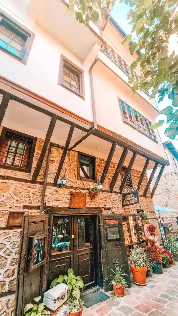A charming traditional guesthouse called “Villa Jovan” stands in the Old Town of Ohrid, with exposed timber beams, a cobbled walkway, and potted plants lining the entrance.