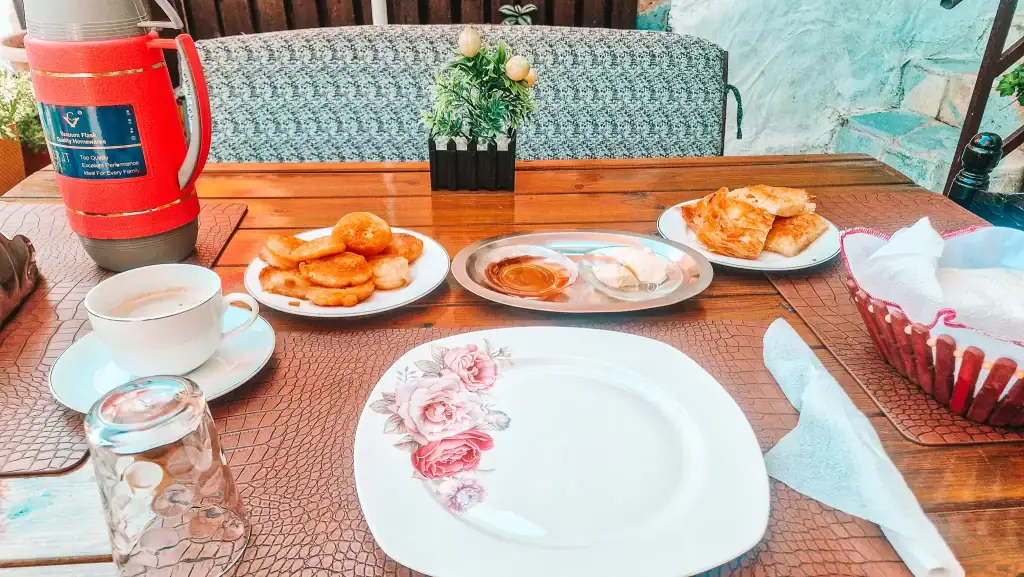 Table set with coffee, fried dough pastries, honey, cheese, bread, and byrek pastries for a traditional Albanian breakfast.