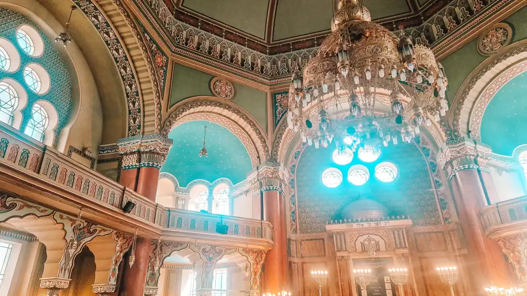 Ornate interior of the Sofia Synagogue, featuring a grand chandelier, stained glass windows, and Moorish Revival architecture with arched ceilings and decorative columns.