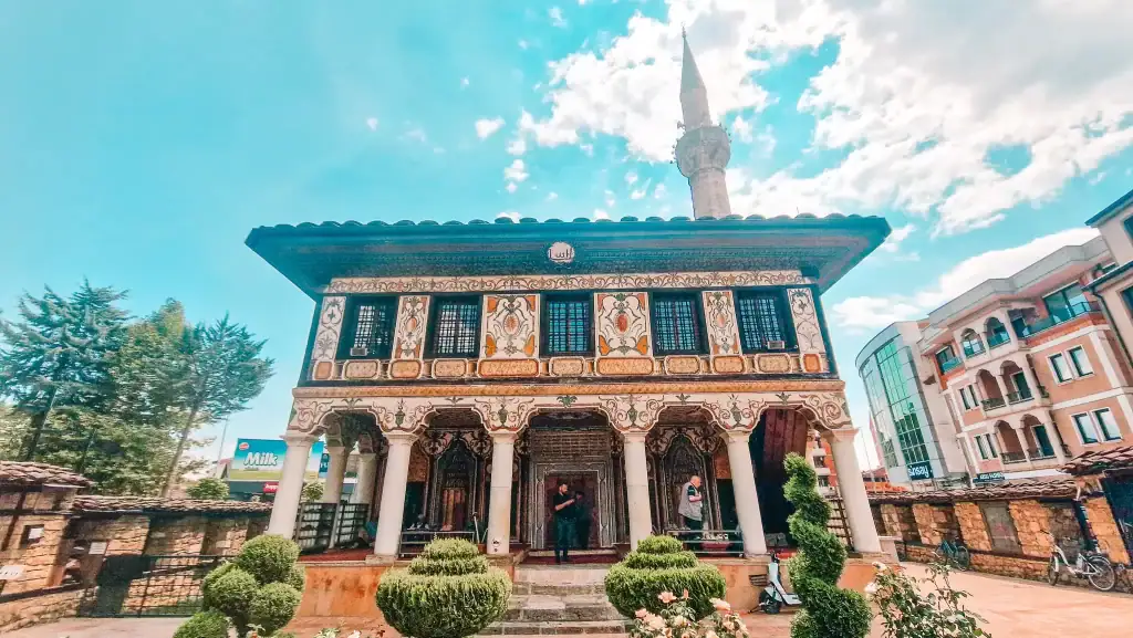 Front view of the Painted Mosque in Tetovo, North Macedonia, known for its elaborately painted façade, decorative columns, and surrounding garden, a standout among Balkan religious landmarks.