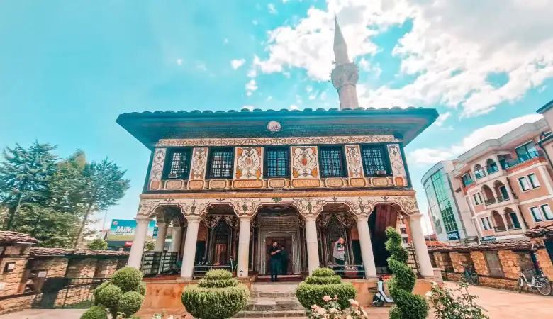 Front view of the Painted Mosque in Tetovo, North Macedonia, known for its elaborately painted façade, decorative columns, and surrounding garden, a standout among Balkan religious landmarks.