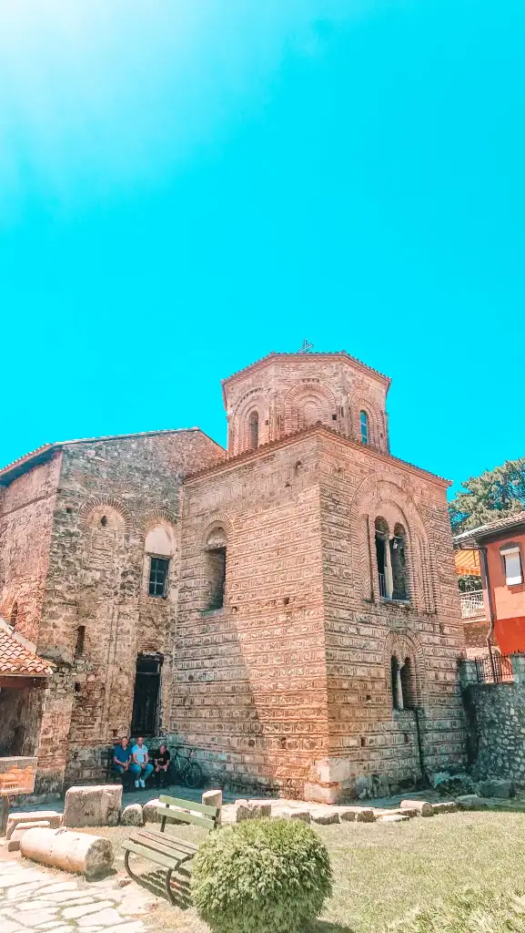 View of the Church of Saint Sophia in Ohrid, North Macedonia, featuring well-preserved Byzantine brick architecture and a domed bell tower surrounded by a garden courtyard.