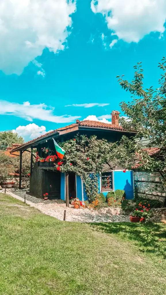 Cosy blue and wood Revival-style house draped in flowering vines and flying the Bulgarian flag, surrounded by a colourful garden. Exploring these homes brings Koprivshtitsa’s 19th-century history to life.