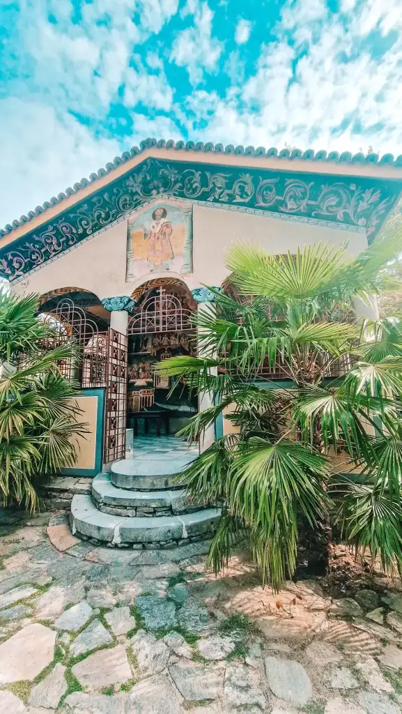 Small chapel at Bachkovo Monastery with painted façade and palm trees in the courtyard, a peaceful stop on day trips from Plovdiv.