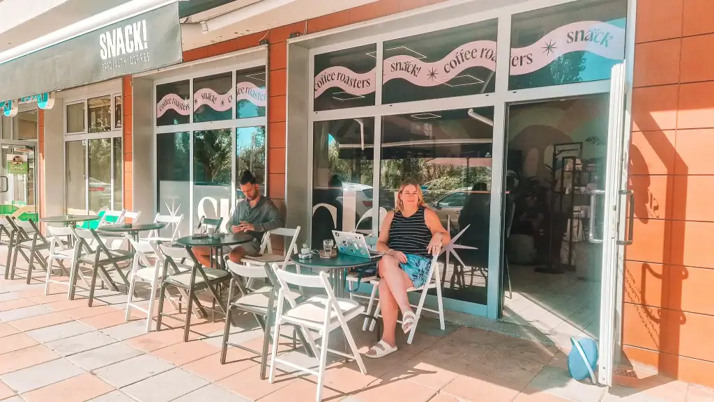 Em sits outside SNACK! Coffee Roasters with her laptop, enjoying the sunshine and fast Wi-Fi—one of the most remote-work-friendly cafés in Plovdiv.