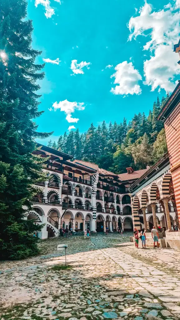 The striped arches and domes of Rila Monastery framed by forested mountains, a highlight of day trips from Plovdiv.