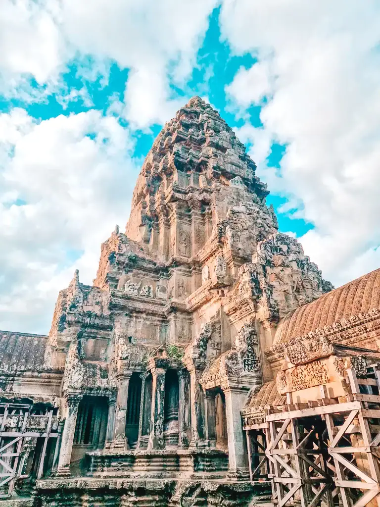 Intricately carved stone tower of Angkor Wat in Cambodia set against a vibrant blue sky, showcasing the grandeur of ancient Khmer architecture.