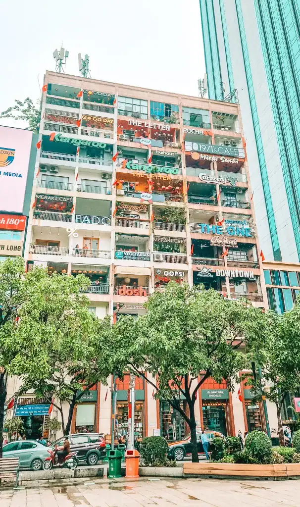The colourful façade of the Café Apartment in Ho Chi Minh City, Vietnam, with balconies full of trendy cafés and bold signage overlooking a lively street.