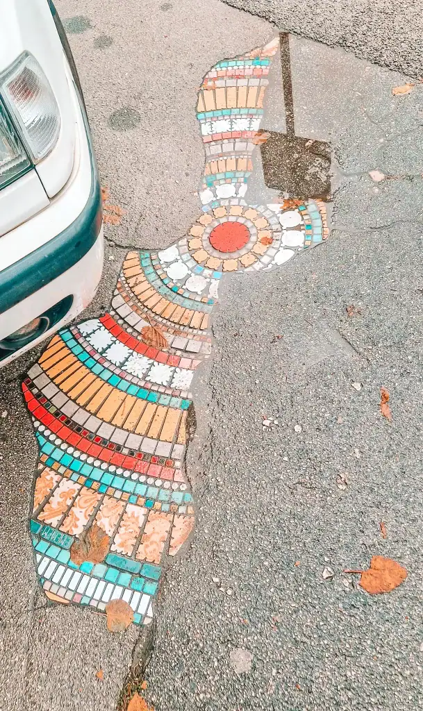 Close-up of a colourful mosaic filling a bomb crater in the street, blending art and activism. This unexpected urban detail adds a creative twist to exploring local streets and hidden gems among the things to do in Mostar.
