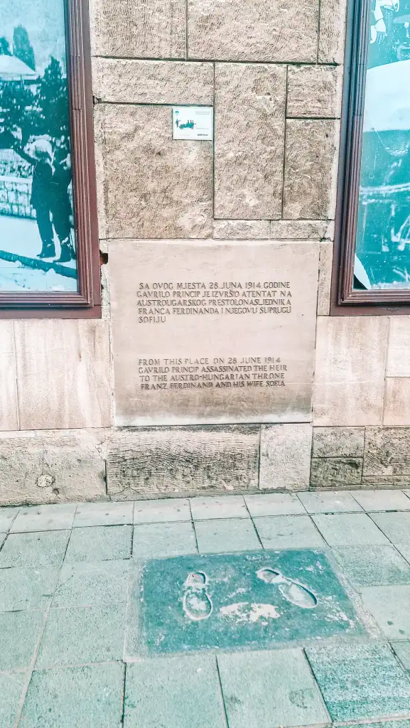 Plaque on a stone wall marking the site where Gavrilo Princip assassinated Archduke Franz Ferdinand in 1914, with footprints embedded in the pavement below. A key historical location tied to the start of World War I and a top site for history lovers visiting Sarajevo.