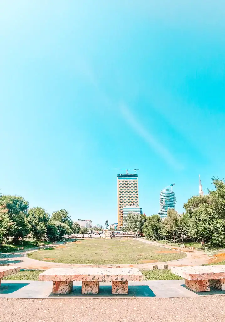 View of Skanderbeg Square in Tirana from a park perspective, with the recognizable Plaza Tirana Hotel and the rotating TID Tower rising behind a statue of national hero Skanderbeg. A key highlight on any 2 week Albania itinerary.