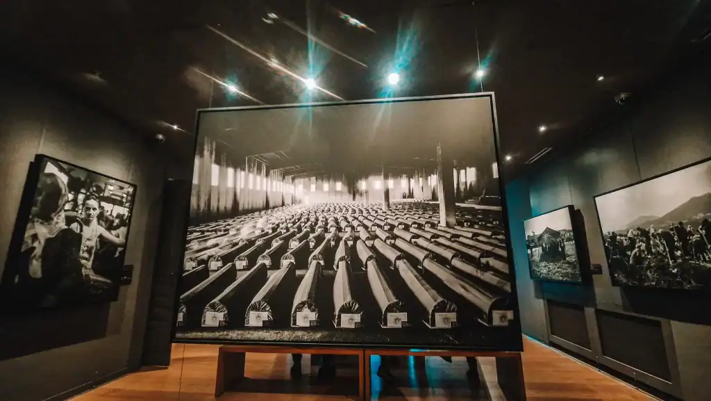 Interior of the Srebrenica Gallery with a large black-and-white photograph showing rows of coffins prepared for burial. The sombre atmosphere highlights Bosnia’s painful recent history and is essential for understanding Sarajevo’s past.