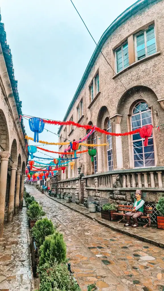 Colourful lanterns hanging above the cobbled Samovodska Charshiya Street in Veliko Tarnovo, lined with historic buildings and artisan shops.