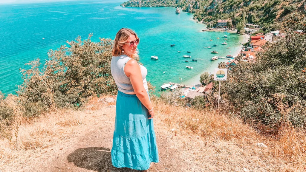 Em looks over the turquoise water and boats of Lake Ohrid from a hillside viewpoint. This shows the kind of weekend escape possible when comparing Skopje vs Tirana for digital nomads.